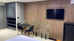 A modern room with a round table, two chairs, a TV mounted on the wall, and built-in shelving. - Taikô Motel by Drops (Porto Alegre)