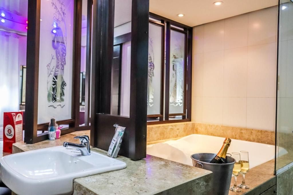 Un baño moderno con un lavamanos grande, una bañera y una botella de champán.