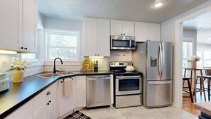 A modern kitchen with stainless steel appliances, a double sink, and a window providing natural light. - Brazos Outpost ~ Ultimate Yard ~ 3BR/2BA (Bryan)