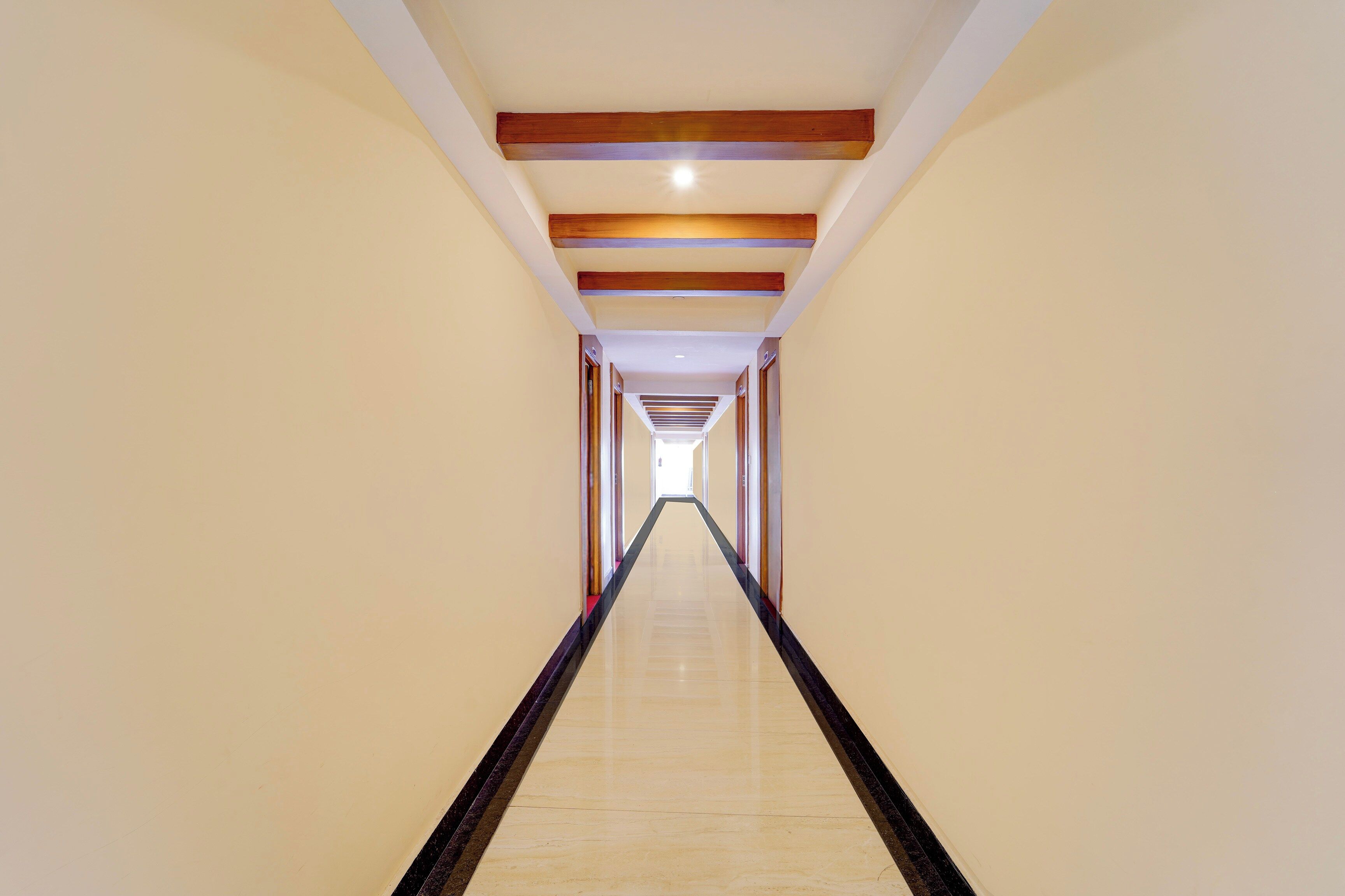 A long, narrow hallway with a polished floor and wooden beams on the ceiling.