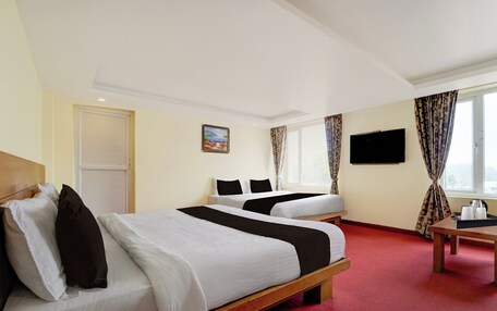 A hotel room with two beds, a television, and a painting on the wall.