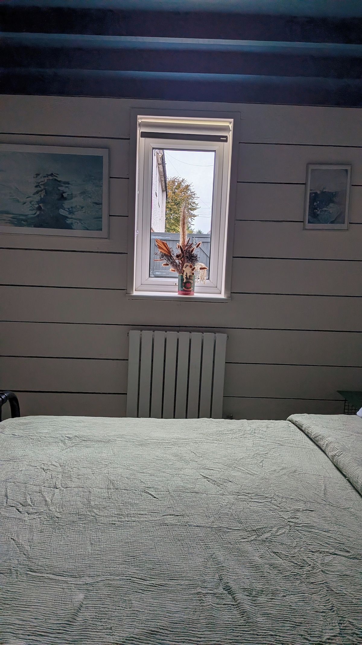 A bedroom with a window, a radiator, and a bed.