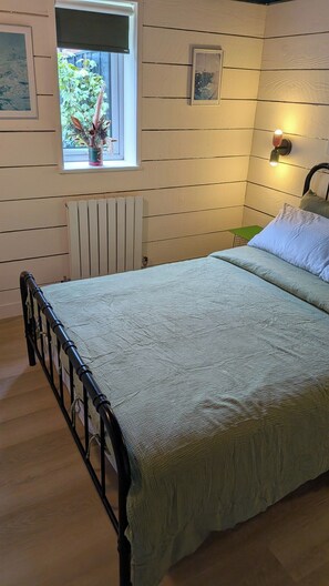Una camera da letto con un letto, una finestra vista verde, un termosifone e un lampadario a parete.