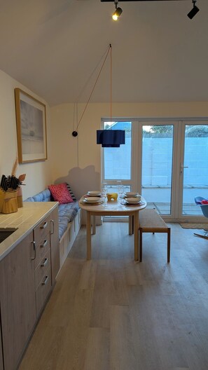 Eine moderne Küche mit Essbereich, Holzschränken und einem großen Fenster mit Blick nach draußen.