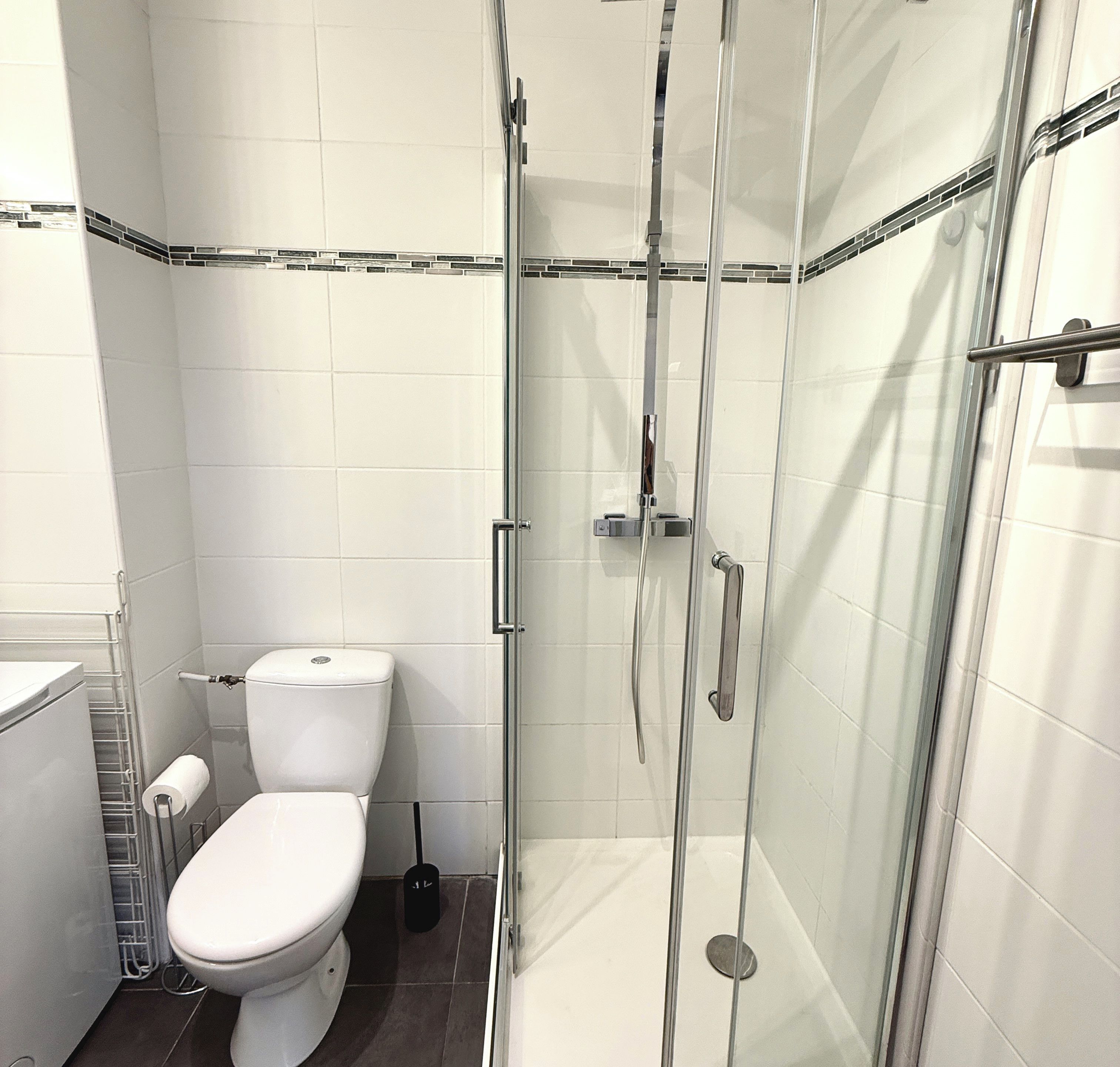 Une salle de bain avec une douche à parois de verre, des toilettes et un porte-serviettes.