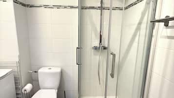 Une salle de bain avec une douche à parois de verre, des toilettes et un porte-serviettes.