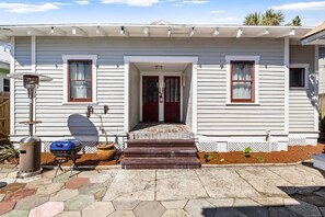 Ett hus med en veranda, en grill och en liten trädgårdsyta.