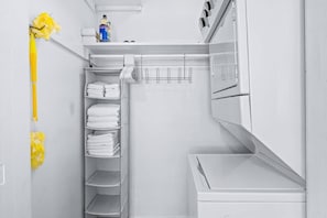 A white laundry room with a drying rack, stacked towels, and a detergent bottle. - King & Queen Bed pet-friendly Downtown St Pete (St. Petersburg)