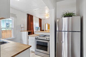 Eine kompakte Küche mit einem Edelstahlkühlschrank, einem Einbauofen und einem Herd.