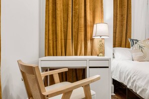 A hotel room with a wooden desk, a chair, a bed with white bedding, a lamp, and curtains. - King & Queen Bed pet-friendly Downtown St Pete (St. Petersburg)