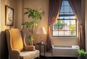 A room with a large window, a chair, a table with a lamp, and an air conditioning unit. - Boutique Hotel Suite for Two in the Historic Oroville Inn (Oroville)