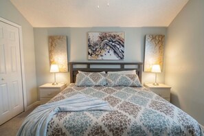 Een slaapkamer met een bed, twee nachtkastjes, een hoofdbord en twee wandlampen.
