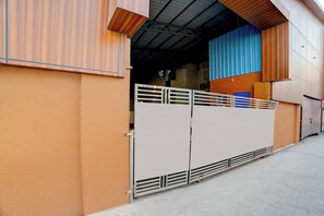 Un edificio con una verja metálica, un muro azul y naranja, y un techo de chapa corrugada.
