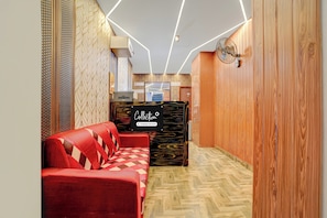A reception area with a red sofa, a wooden reception desk, and a patterned wall. - Super Collection O Kovur (Chennai)