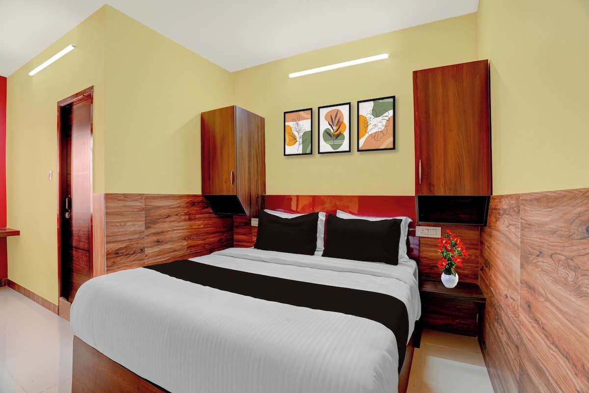 A hotel room with a bed, wooden headboard, a wall-mounted TV, and three framed artworks.