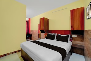 A hotel room with a bed, wooden headboard, and a red accent wall. - Super Collection O Kovur (Chennai)