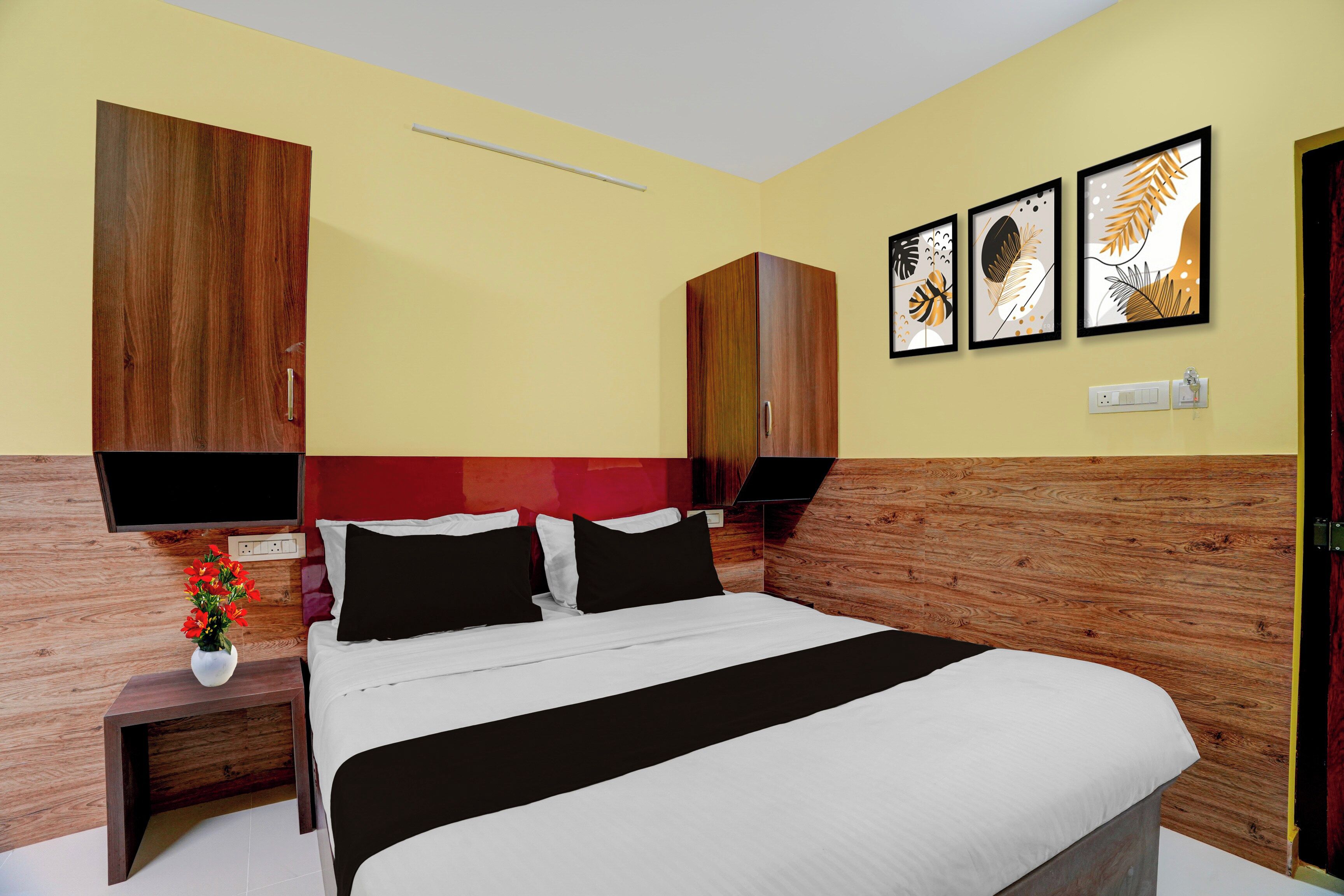 Una habitación de hotel con cama, mesitas de noche, un florero y decoración en la pared.