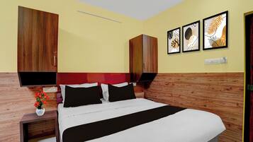 Una habitación de hotel con cama, mesitas de noche, un florero y decoración en la pared.