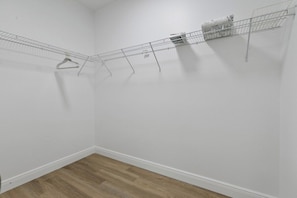 A room with a wooden floor, white walls, and a metal drying rack with clothes. - Sunshine Retreat | NEW 4/2, King Bed, Near Beaches (Port Charlotte)