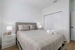 Ein Schlafzimmer mit einem Bett, Nachttischen, einer Lampe und einer Tür.