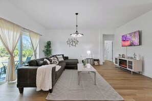 Ein modernes Wohnzimmer mit einer Couch, einem Couchtisch und einem Fernseher.