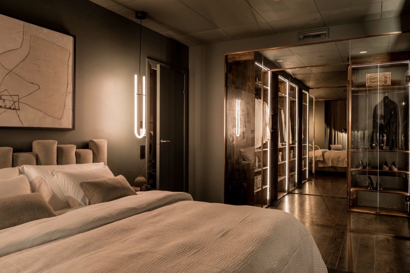 A modern bedroom with a large bed, a wardrobe, and a mirror.