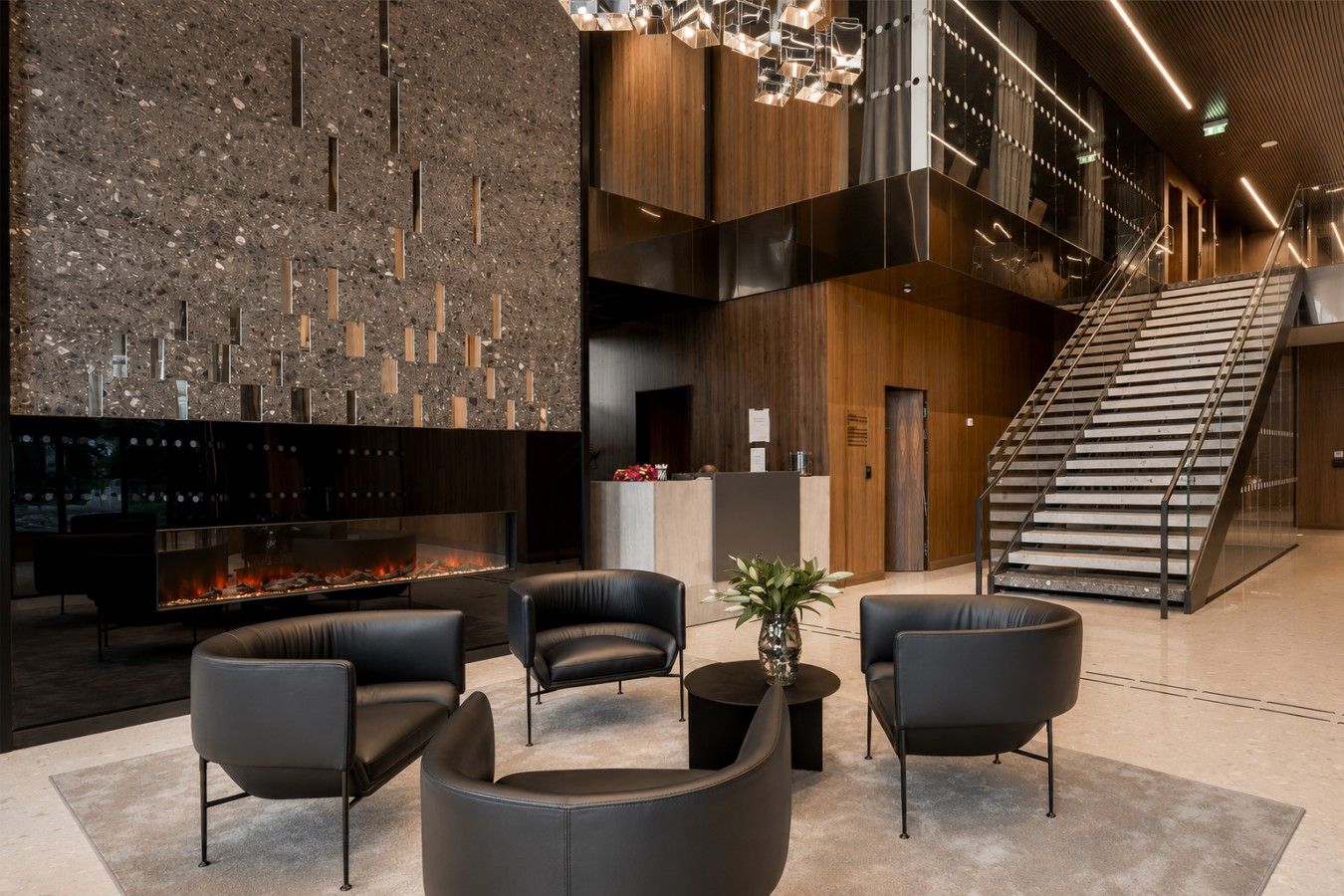 A modern lobby with a fireplace, seating area, and a staircase.