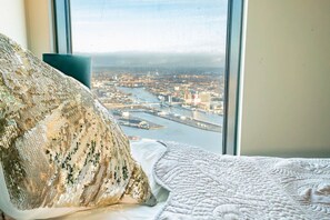 A bed with a view of a cityscape through a window. - Karlatornet Penthouse View (Lindholmen)