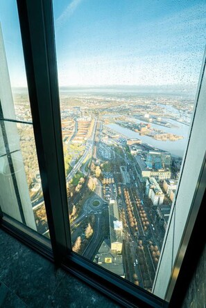 A high-rise building with a view of a cityscape, including roads and a river.