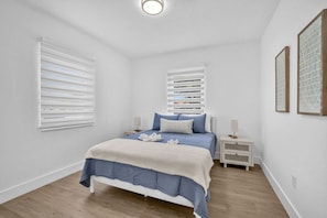 A bedroom with a bed, bedside tables, and a window with blinds. - The 280 House | Newly Renovated Near Miami Airport (Miami)