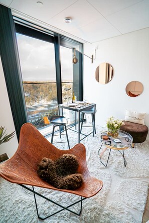 Un espace de vie moderne doté d’une grande fenêtre, d’un coin repas et d’un espace salon confortable.