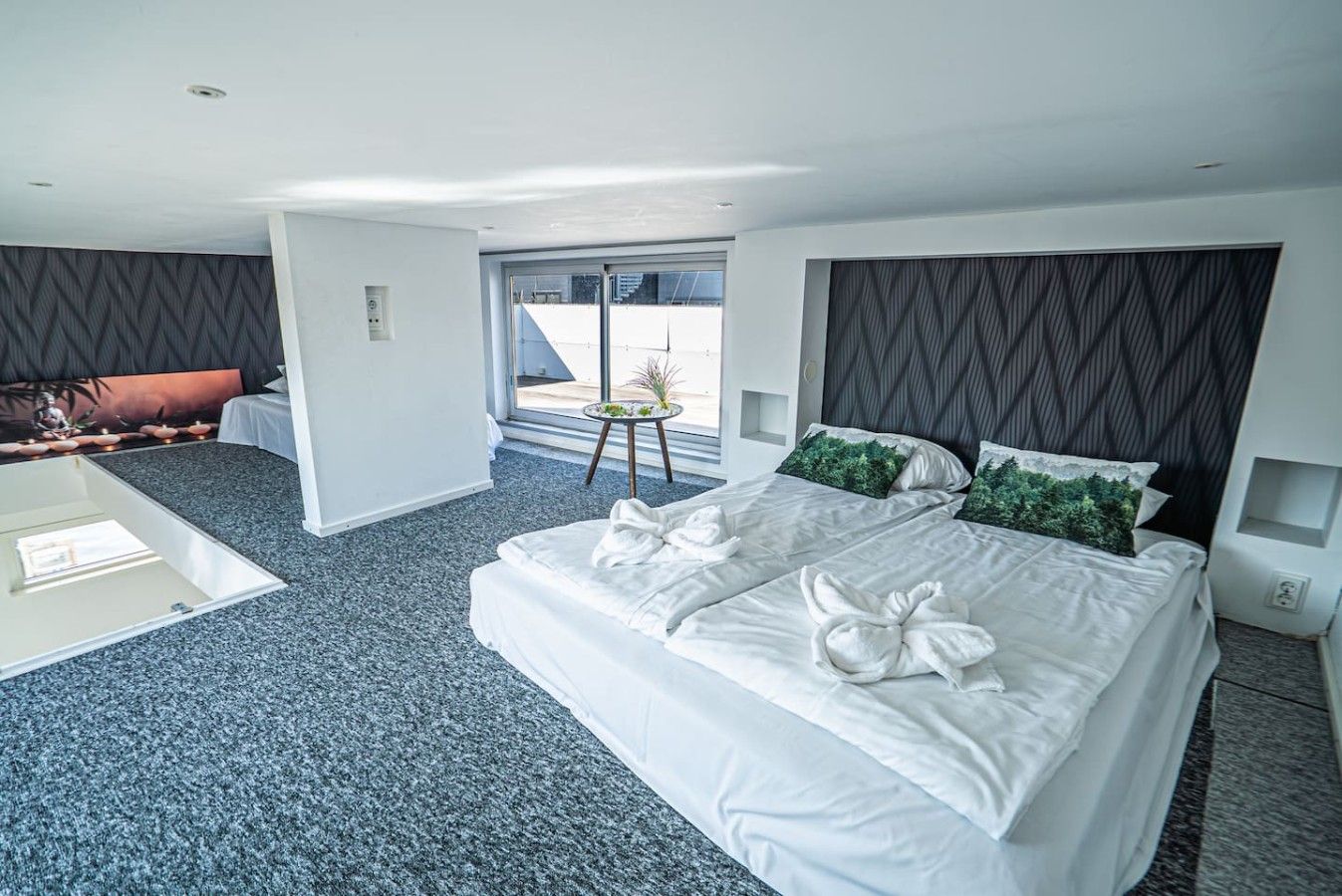 Et moderne hotelværelse med en stor seng, et lille bord og udsigt til det fri.