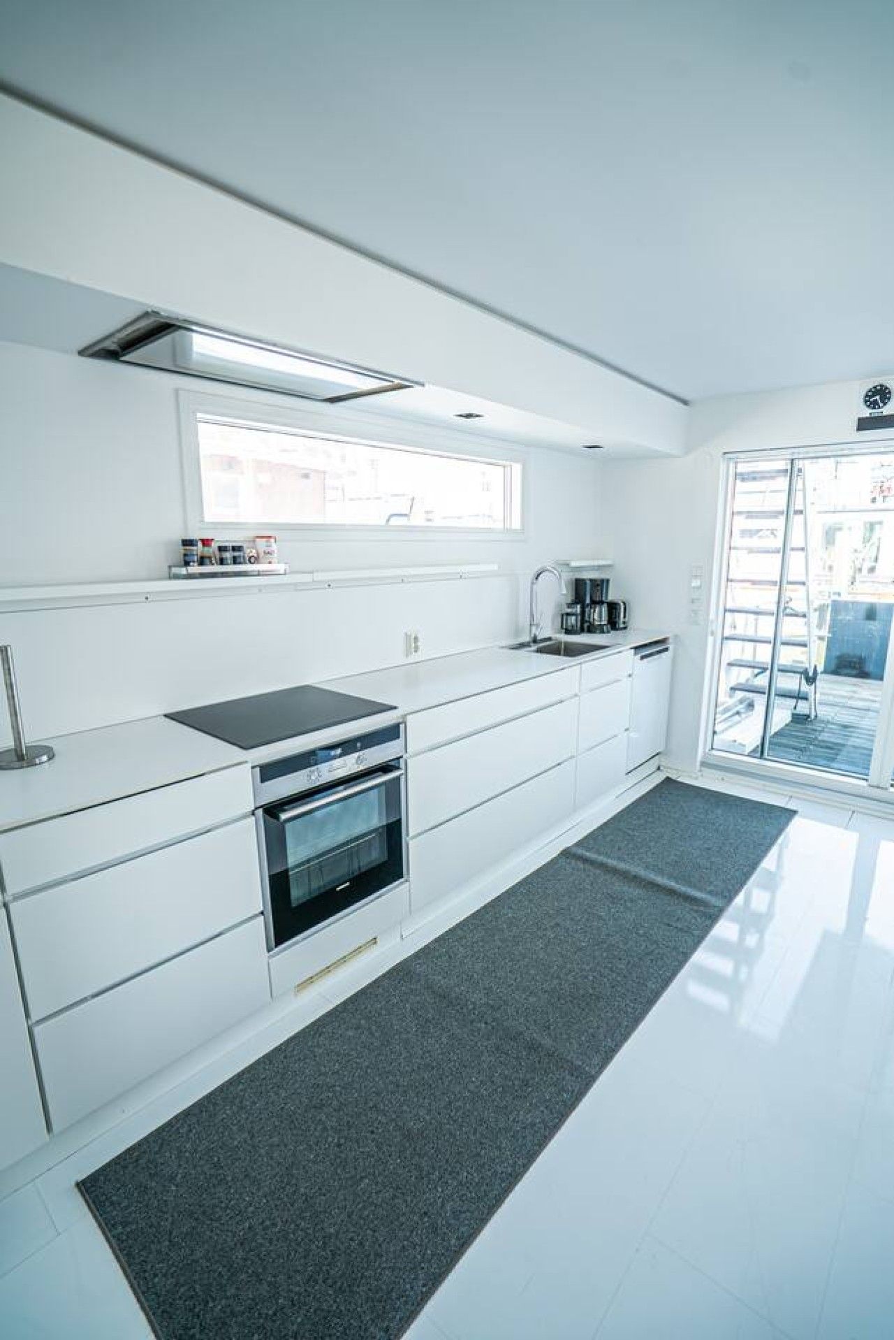 A modern kitchen with white cabinetry, a built-in oven, and a window above the sink.