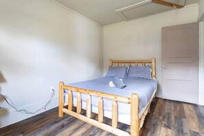Ein Schlafzimmer mit einem hölzernen Bett, einer grauen Matratze und einem Holz-Kopfteil.