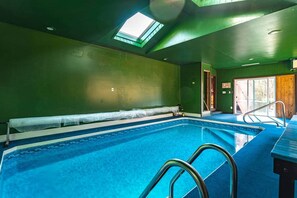 Una piscina interior con tragaluces, una escalera de piscina y vistas al exterior.