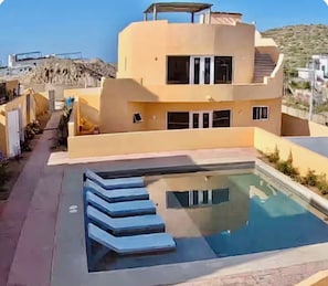 Ein modernes Gebäude mit Schwimmbad und Treppen, die zu einem überdachten Bereich führen.