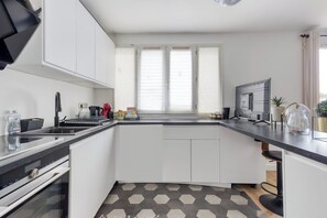 Eine moderne Küche mit weißen Schränken, einer schwarzen Arbeitsplatte und einem eingebauten Backofen.