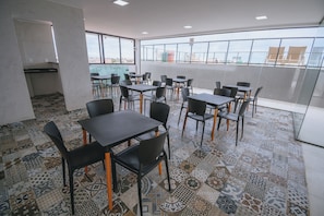 A modern dining area with tables and chairs, large windows, and a patterned floor. - New Listing (Ipojuca)