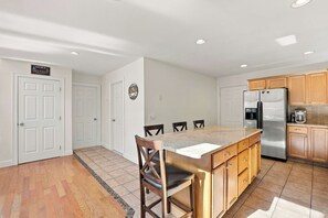 A kitchen with a central island, wooden cabinets, a stainless steel refrigerator, and a tiled floor. - Mountain Lodge | 4BR + Game Room (Bartlett)