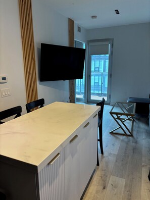 A modern living room with a large TV mounted on the wall, a wooden accent wall, and a glass coffee table. - 5 minutes to the city life. Sleeps 6 (4adults + 2kids) Central downtown Toronto. (Toronto)