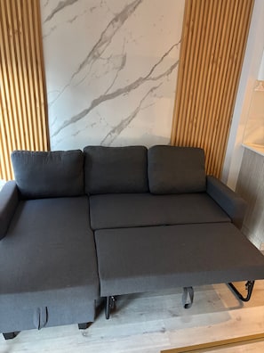 A sectional sofa with a wooden slat wall and a marble-patterned wall behind it. - 5 minutes to the city life. Sleeps 6 (4adults + 2kids) Central downtown Toronto. (Toronto)
