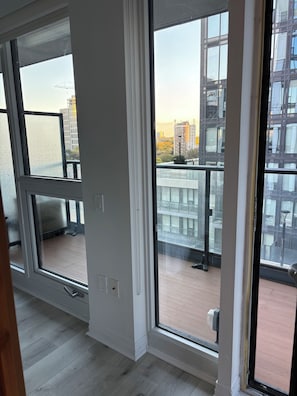 A room with large windows, a wooden floor, and a view of a cityscape with buildings and a construction crane. - 5 minutes to the city life. Sleeps 6 (4adults + 2kids) Central downtown Toronto. (Toronto)