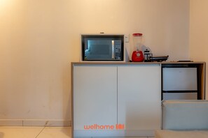 A compact kitchenette with a microwave, a small refrigerator, and a coffee maker on the countertop. - Apartamento em Balneario Picarras Proximo da Praia (Piçarras)