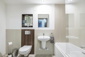 A modern bathroom with a toilet, sink, and bathtub. - Battersea River View Apartment (London)