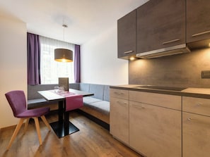 A modern kitchen with a built-in stove, wooden cabinets, and a dining area with a table and chairs. - Augl´s Hof by Interhome (Ischgl)