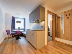 A compact kitchen with a dining area, wooden flooring, and a view of a wooden door. - Augl´s Hof by Interhome (Ischgl)