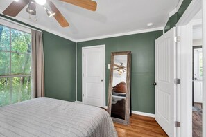 A bedroom with a bed, a ceiling fan, a large mirror, and a view of a bedroom with a bed and a ceiling fan. - The Bayou Sanctuary | Peaceful Wooded Retreat (Ponchatoula)