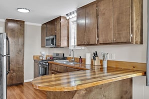 A kitchen with wooden cabinets, a microwave, a stove, and a sink.