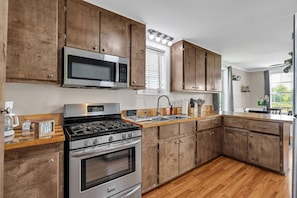 A modern kitchen with wooden cabinets, stainless steel appliances, and a wooden countertop. - The Bayou Sanctuary | Peaceful Wooded Retreat (Ponchatoula)