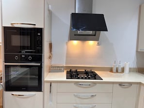 A kitchen with a built-in oven, microwave, and gas stove. - New Listing (Chéraga)